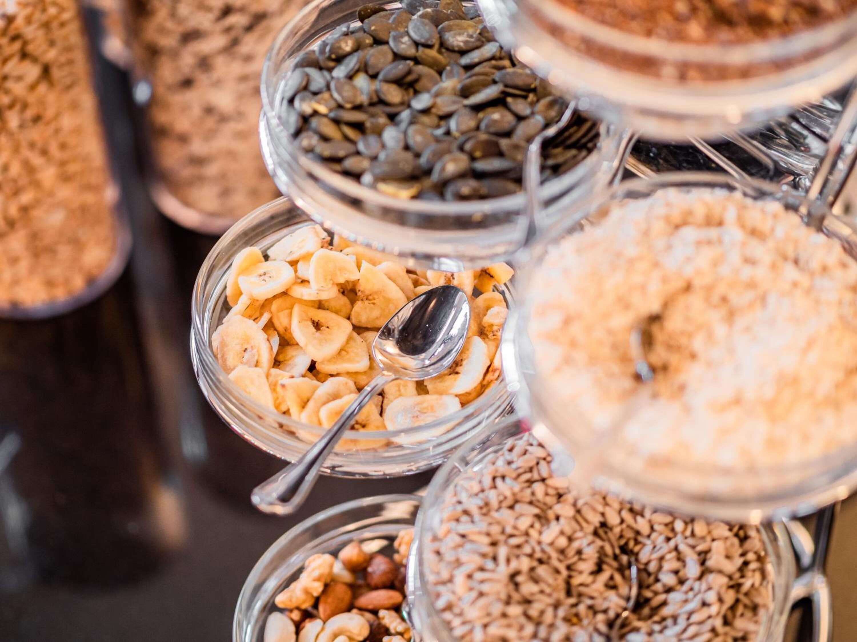 A variety of food items in glass containers, including nuts, seeds, and dried fruits.