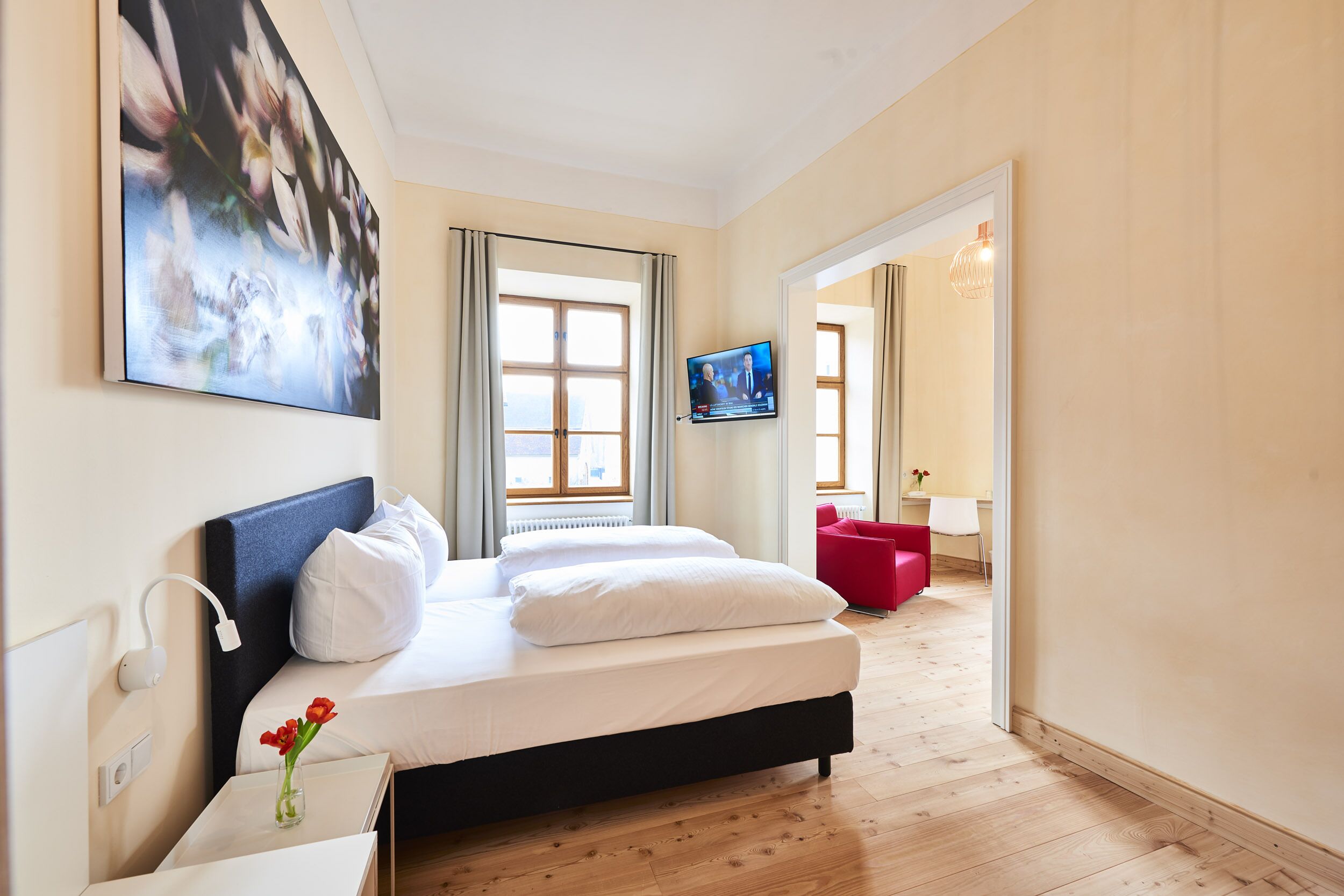 Habitación de hotel moderna con una cama grande, un televisor de pantalla plana y vistas a la ciudad desde la ventana.