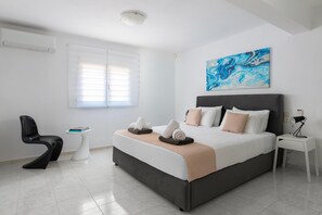 Une chambre à coucher moderne, avec un lit, une table de chevet, une chaise et une œuvre d’art accrochée au mur.