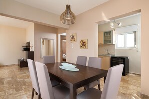 Un coin repas avec une table en bois foncé, six chaises, un luminaire suspendu et des œuvres d’art accrochées au mur.