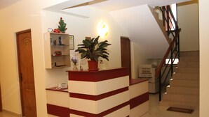 A reception desk with a potted plant, a small Christmas tree, and a wall-mounted light fixture. - Pensiunea Maria (Floresti)