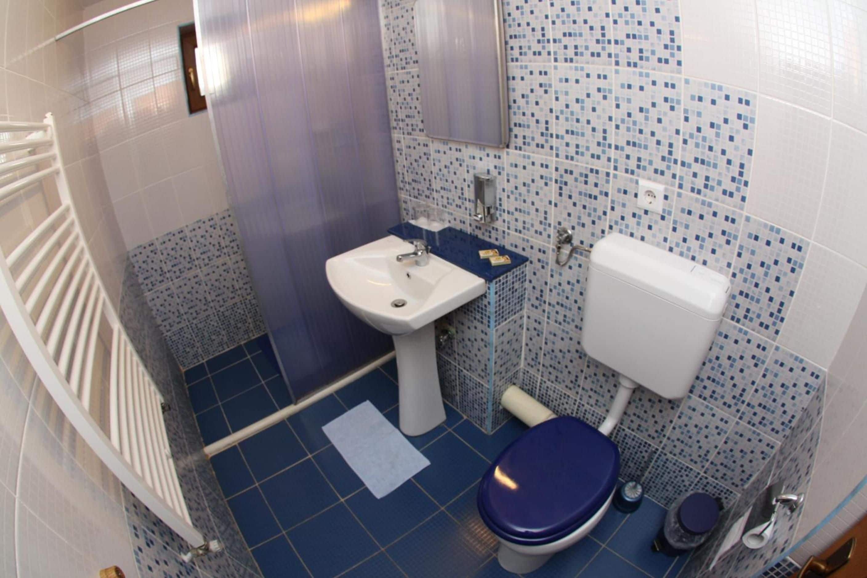 A small bathroom with a white sink, a toilet, and a shower area.