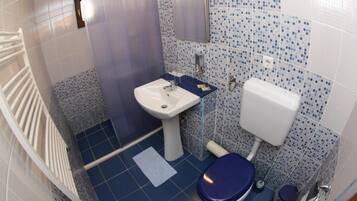 A small bathroom with a white sink, a toilet, and a shower area.
