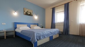 A hotel room with a single bed, a nightstand, a wall-mounted light, and a window with curtains. - Pensiunea Maria (Floresti)