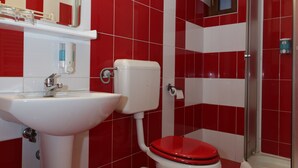 A bathroom with red and white tiles, a white sink, a toilet, and a shower area. - Pensiunea Maria (Floresti)