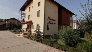 A two-story building with a beige facade and a red roof. The name 'Pension Maria' is visible on the side. - Pensiunea Maria (Floresti)