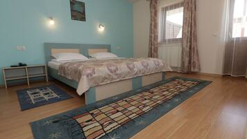 A bedroom with a bed, a nightstand, a window with curtains, and a patterned rug.