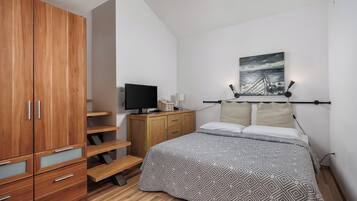 A bedroom with a bed, a TV, a painting, and a wardrobe.