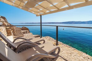 A seaside terrace with lounge chairs, a pergola, and a clear view of the sea. - Villa with pool and private waterfront (Jablanac)