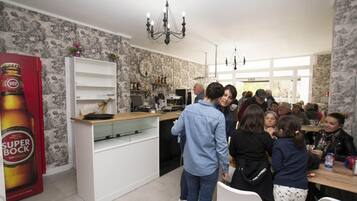 Una cocina moderna con muebles blancos, una araña y un gran anuncio de cerveza Super Bock.