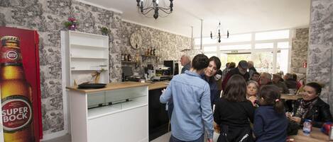 Una cocina moderna con muebles blancos, una araña y un gran anuncio de cerveza Super Bock.