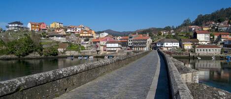 Un puente de piedra que lleva a un pueblo con edificios de colores y un río.