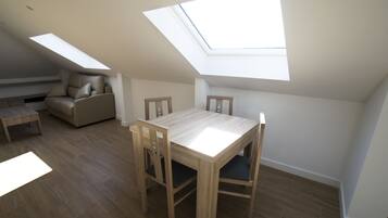 A room with a skylight, a dining table with chairs, and a sofa.