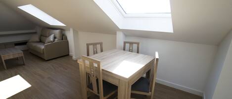 Una habitación con tragaluz, una mesa de comedor con sillas y un sofá.
