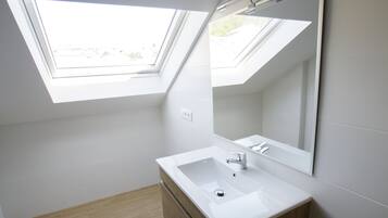 Un baño moderno con tragaluces, un lavamanos blanco y un mueble de tocador de madera.