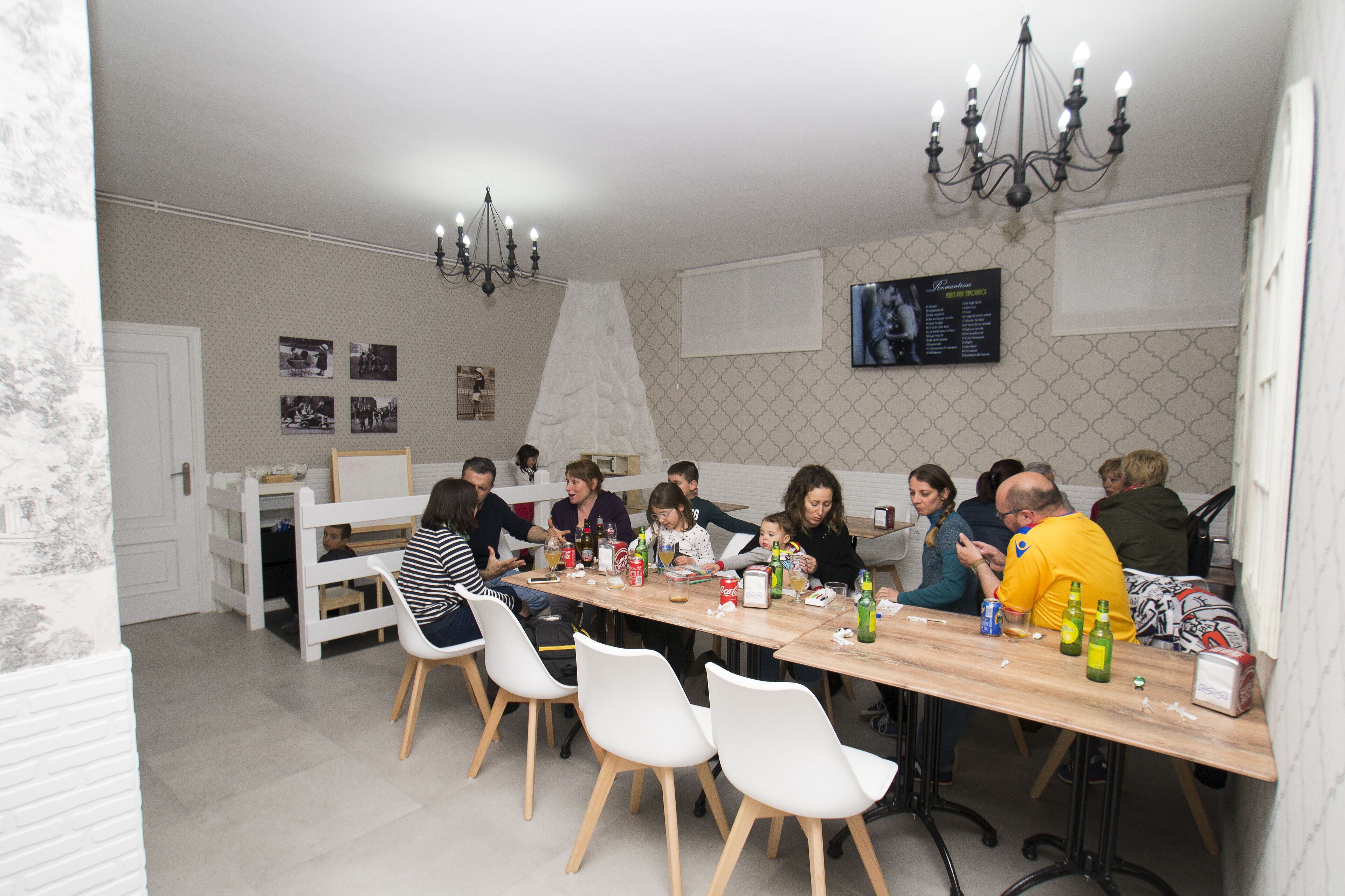 A dining area with a long wooden table, white chairs, and a chandelier.