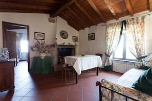 A cozy room with a fireplace, a dining table, and a sofa.