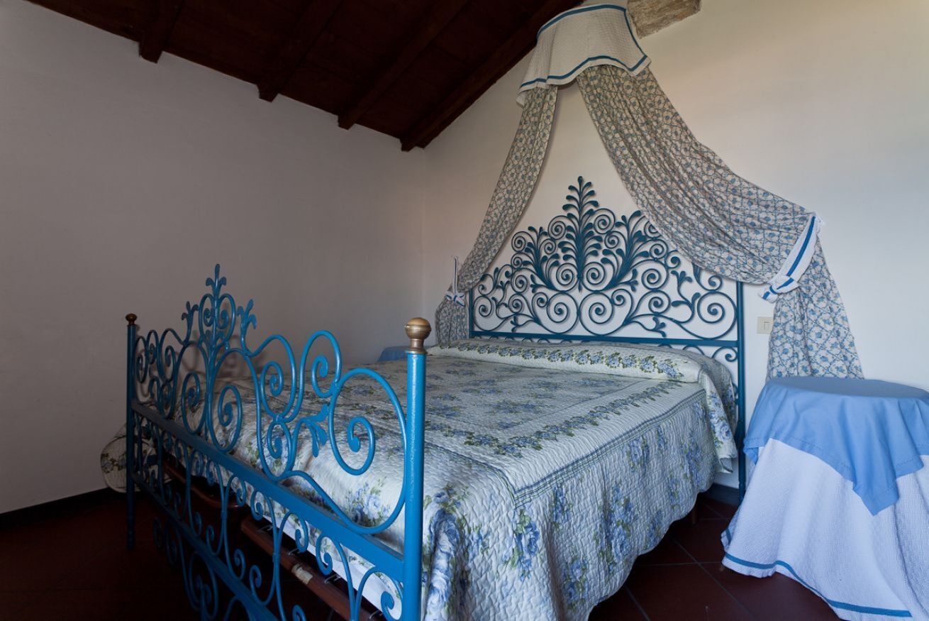 Ein Zimmer mit einem Bett, das einen blauen Metallrahmen und ein Baldachin mit Blumenmuster hat.