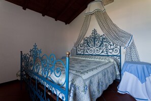 A room with a bed featuring a blue metal frame and a canopy with a floral pattern.