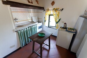 A compact kitchen with a tiled backsplash, a wooden table, a refrigerator, and a window with curtains. - Three-room apartment with breathtaking view 10 minutes from the 5 Terre, free Wi (La Spezia)