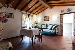 A cozy room with a wooden ceiling, a dining table with chairs, a sofa with patterned cushions, and a painting on the wall. - Three-room apartment with breathtaking view 10 minutes from the 5 Terre, free Wi (La Spezia)