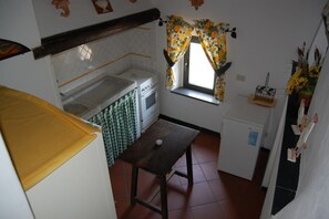 A compact kitchen with a stove, oven, and a small window with floral curtains.