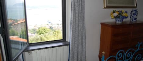 Un dormitorio con ventana, cómoda de madera y cama con cabecera azul.