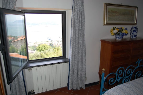 A bedroom with a window, a wooden dresser, and a bed with a blue headboard.