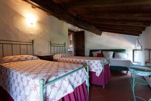 A room with two beds, a wooden ceiling, and a small table.