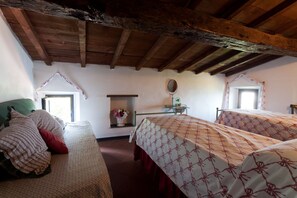 A rustic bedroom with two beds, wooden beams on the ceiling, a small table with a mirror, and a window with curtains. - Three-room apartment with breathtaking view 10 minutes from the 5 Terre, free Wi (La Spezia)