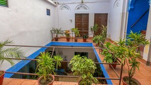 Une cour agrémentée de plantes en pot, une piscine aux carreaux bleus et une porte de style traditionnel.