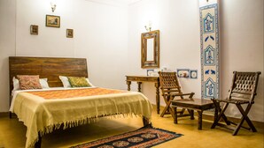 Une chambre à coucher avec un lit en bois, un bureau, deux chaises, un miroir et des panneaux décoratifs sur les murs.