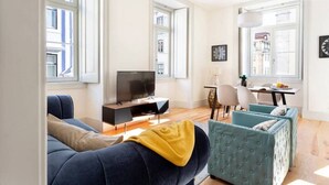 Una sala moderna con sofá, televisión y comedor con sillas y mesa.