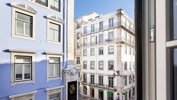 Vista de una calle estrecha flanqueada por edificios con diversos estilos arquitectónicos, bajo un cielo azul despejado.