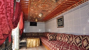A room with a patterned wall, a sofa, a small table, and a decorative ceiling. - Riad Royal (Meknes)