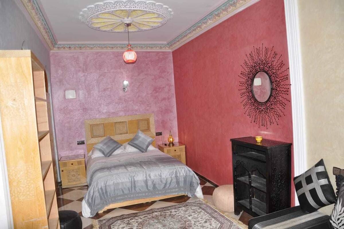 A bedroom with a bed, nightstands, a dresser, and a decorative mirror.