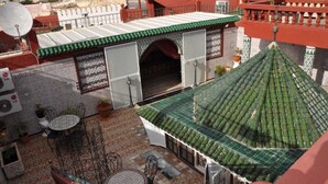 A rooftop terrace with a green tiled roof, a white wall with a decorative arch, and a satellite dish. - Riad Royal (Meknes)