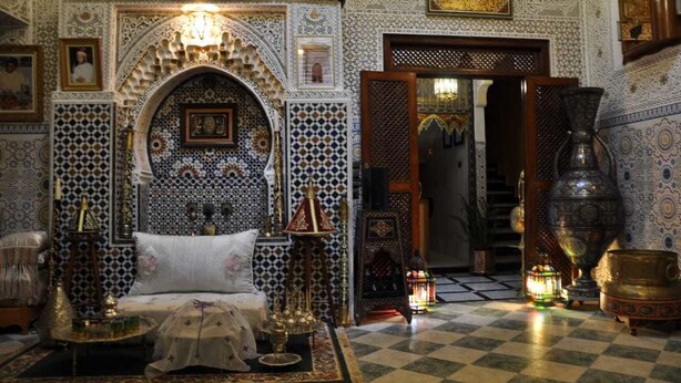 A room with intricate tile patterns, a bed with a decorative headboard, and traditional lamps. - Riad Royal (Meknes)