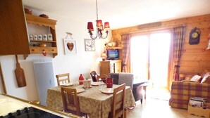 A cozy kitchen with a dining area, wooden cabinets, and a television. - APARTMENT AT THE FOOT OF THE SLOPES (Villard-sur-Doron)