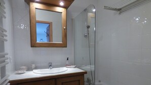 A bathroom with a wooden vanity, a white sink, a mirror, and a glass-enclosed shower. - APARTMENT AT THE FOOT OF THE SLOPES (Villard-sur-Doron)