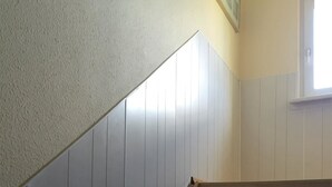 Una escalera con escalones de madera y paneles blancos en las paredes.