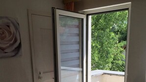 Una habitación con una cama, un puerta corrediza de vidrio que da a un balcón y un radiador.