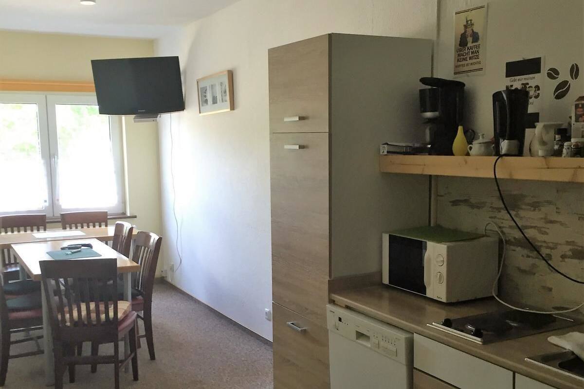 A compact kitchen with a microwave, coffee maker, and a small dishwasher. There is a dining area with a table and chairs.