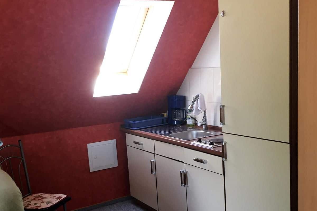A compact kitchen with a window, a sink, a coffee maker, and a refrigerator.