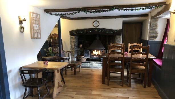 A cozy interior with a wooden table and chairs, a fireplace, and a clock on the wall. - Blue Lion Inn (Okehampton)