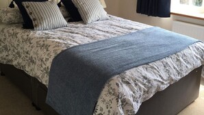 A bedroom with a bed, a window with curtains, and a radiator. - Blue Lion Inn (Okehampton)