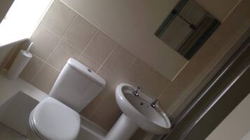 Un baño con inodoro, lavamanos y espejo en la pared.