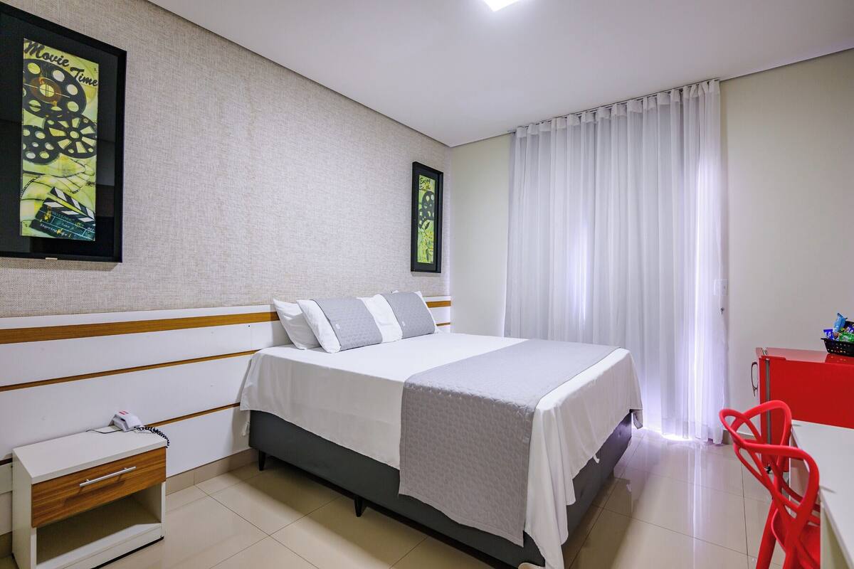 Une chambre d’hôtel avec un lit, un bureau, une chaise et une table de chevet.