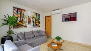 A modern living room with a grey sofa, a coffee table, and a large painting on the wall. - OYO Tropical Confort Hotel, Brasilia (São Sebastião)