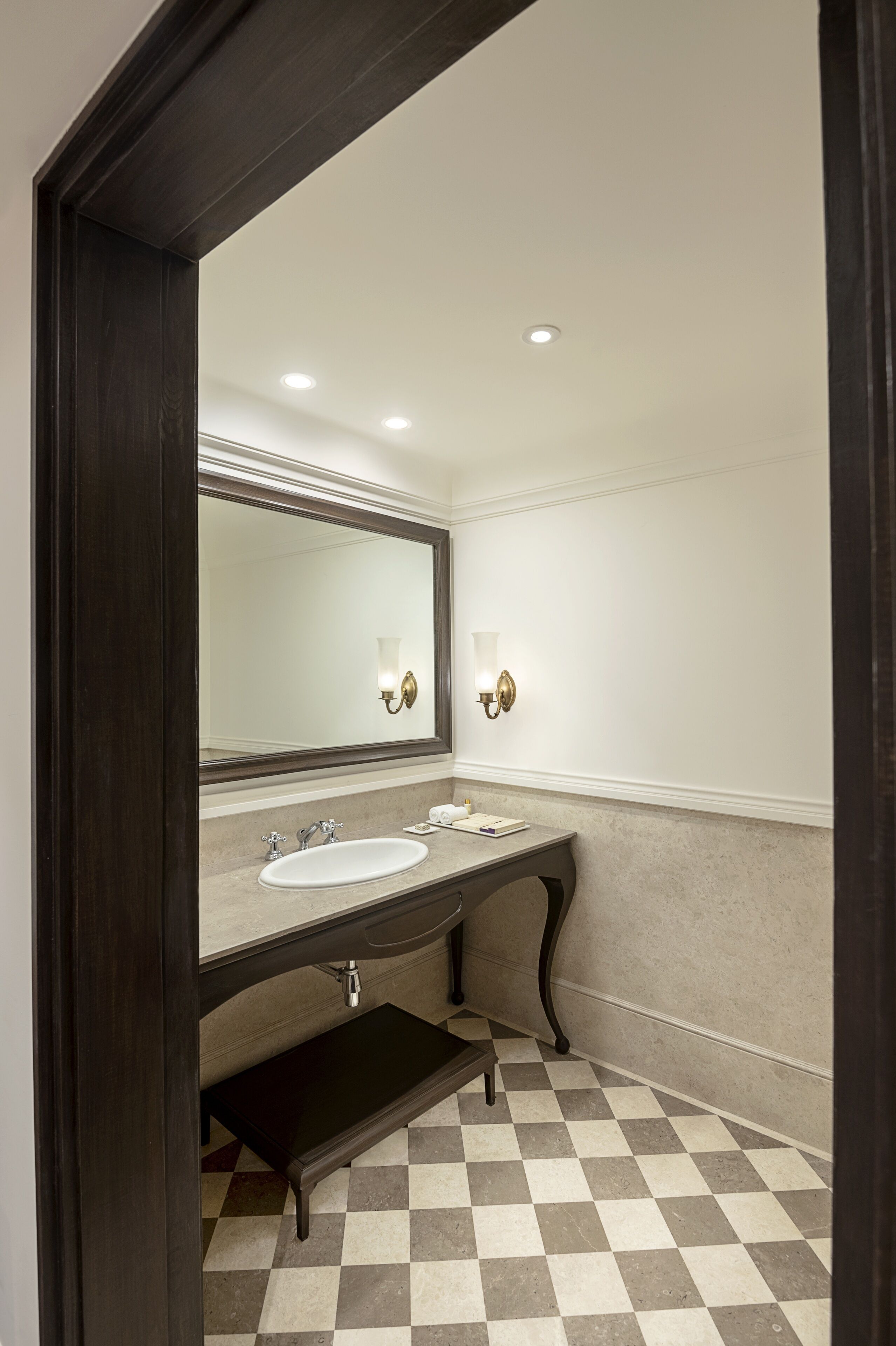 A bathroom with a large mirror, two sinks, a vanity, and a checkered floor.
